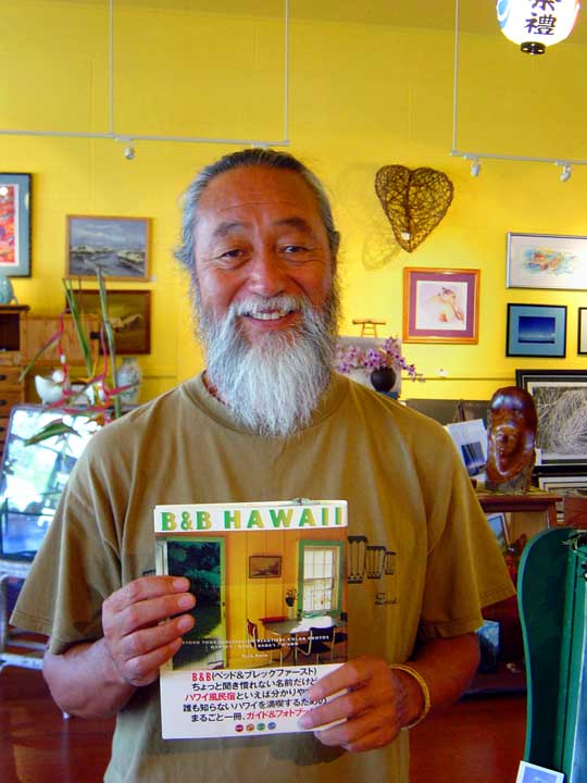 ハワイ島を代表する、写真家・随筆家・アーティスト、 代表作「B&B HAWAII」を手にするニック加藤氏